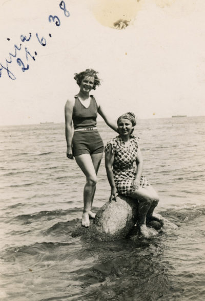 Dwie kobiety pozujące na głazie zanurzonym w morzu